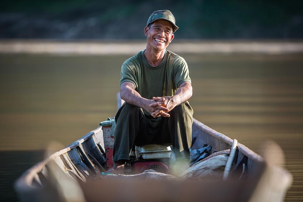 Voyage responsable Laos croisière bateau homme qui sourit